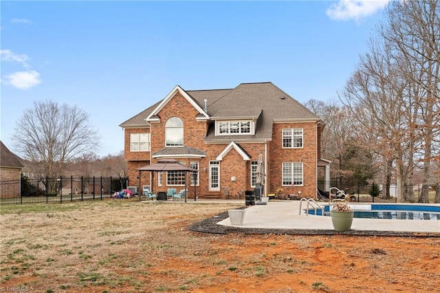 rear view of house with a patio area, a fenced in pool, brick siding, and fence