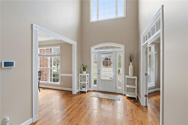 entryway with baseboards, a high ceiling, and wood finished floors