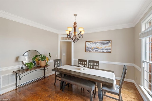 dining room featuring an inviting chandelier, wood finished floors, baseboards, and ornamental molding