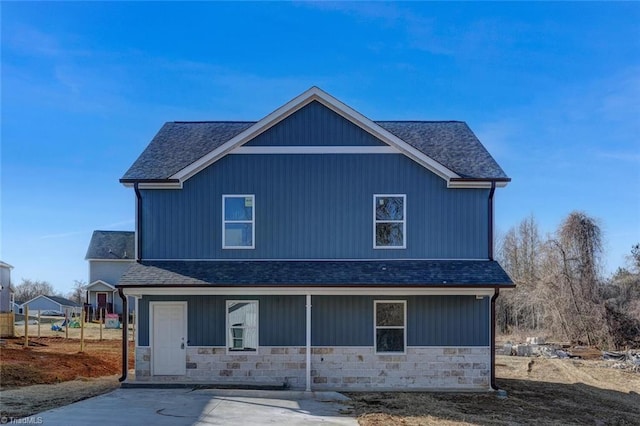 view of front of property featuring stone siding and a shingled roof