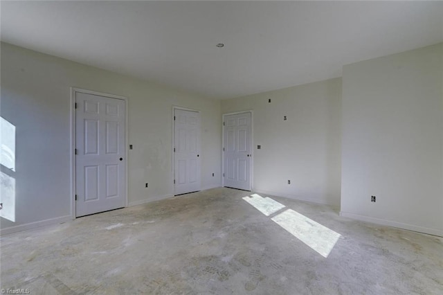 spare room featuring baseboards and concrete floors