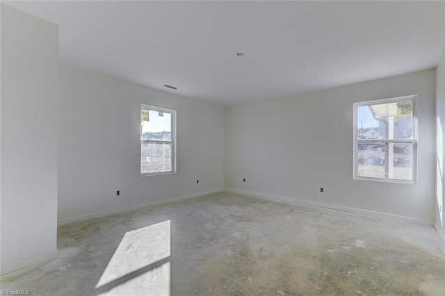 unfurnished room featuring baseboards, plenty of natural light, and concrete floors