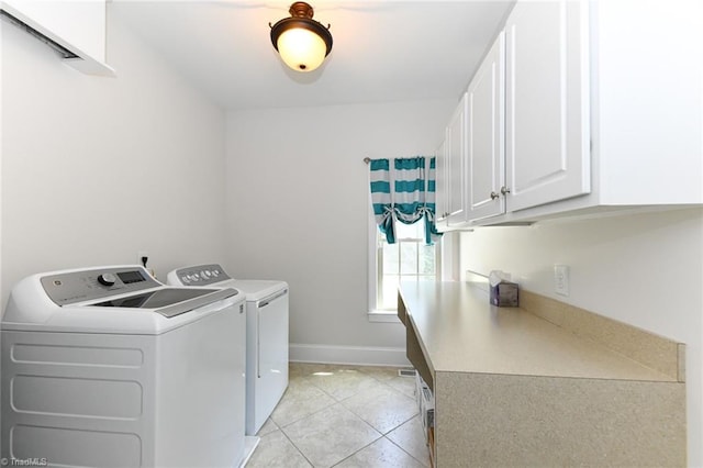 laundry room featuring light tile patterned floors, baseboards, washing machine and dryer, and cabinet space