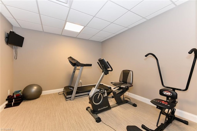 exercise area featuring baseboards, carpet, and a paneled ceiling