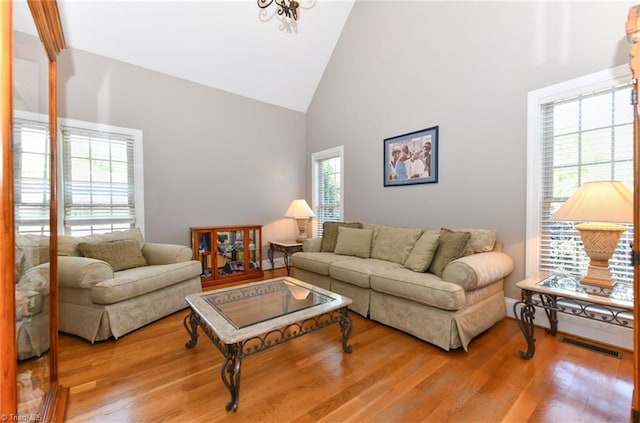 living area featuring visible vents, wood finished floors, and high vaulted ceiling