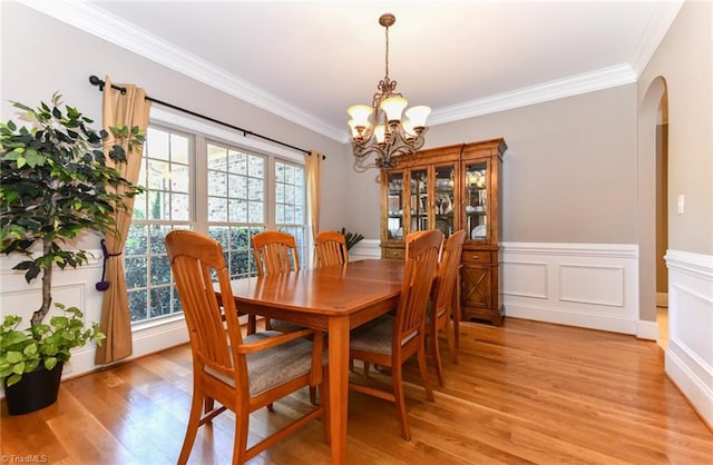 dining area featuring light wood-style floors, arched walkways, a notable chandelier, and a healthy amount of sunlight