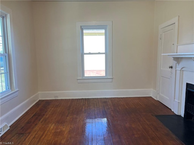 unfurnished living room featuring dark wood-type flooring and a healthy amount of sunlight