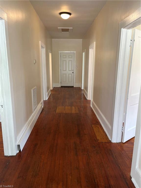 corridor with dark hardwood / wood-style flooring