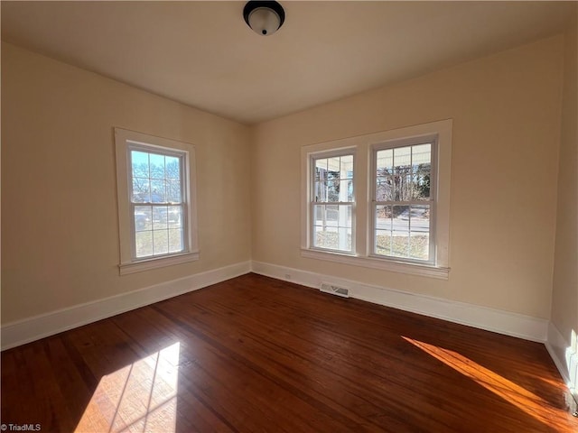 unfurnished room with a healthy amount of sunlight and dark wood-type flooring