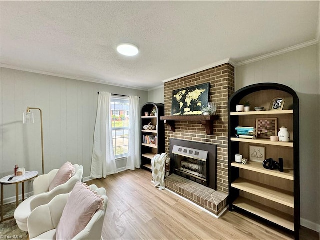 living room with a brick fireplace, a textured ceiling, wooden walls, crown molding, and hardwood / wood-style flooring