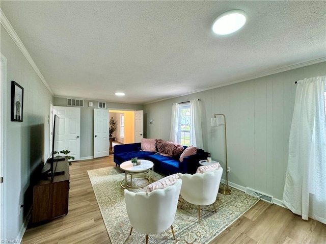 living room featuring ornamental molding, a textured ceiling, and light wood-type flooring