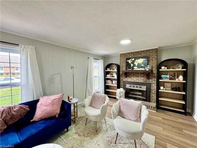 living room with a brick fireplace, plenty of natural light, a textured ceiling, and light wood-type flooring