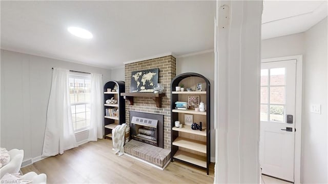 living room featuring a healthy amount of sunlight, light hardwood / wood-style floors, a fireplace, and ornamental molding