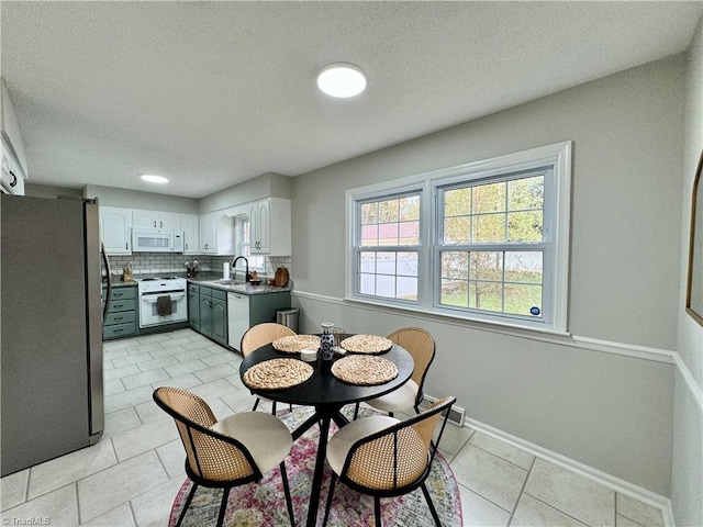 kitchen featuring tasteful backsplash, a textured ceiling, white appliances, sink, and white cabinets