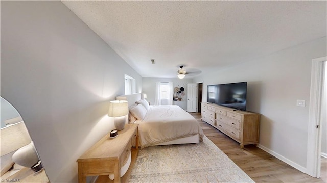 bedroom featuring ceiling fan, light hardwood / wood-style flooring, and a textured ceiling