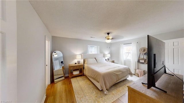 bedroom with ceiling fan, a textured ceiling, and light wood-type flooring