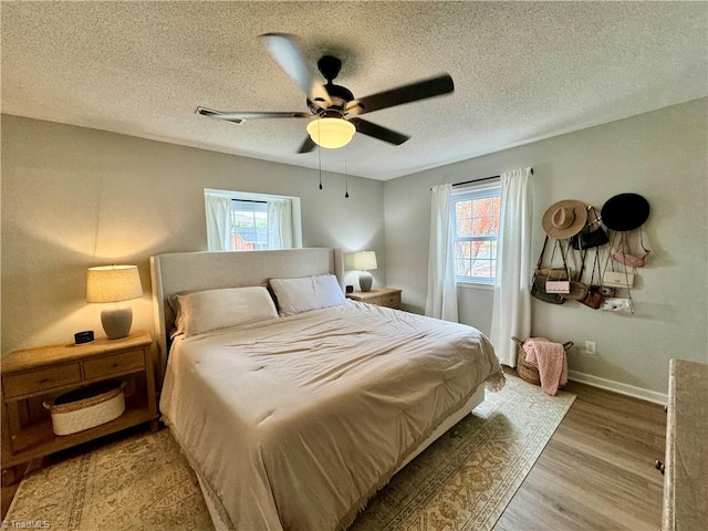 bedroom featuring ceiling fan, light hardwood / wood-style floors, and a textured ceiling