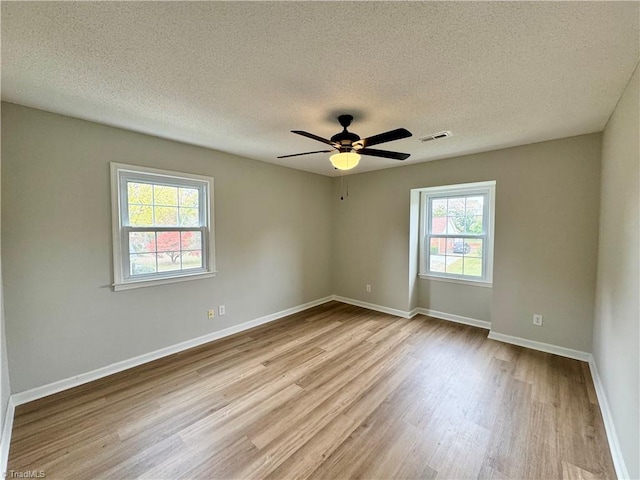 unfurnished room featuring a textured ceiling, light wood-type flooring, plenty of natural light, and ceiling fan