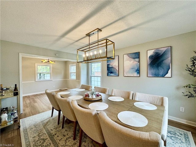 dining room with dark hardwood / wood-style flooring, a chandelier, and a textured ceiling