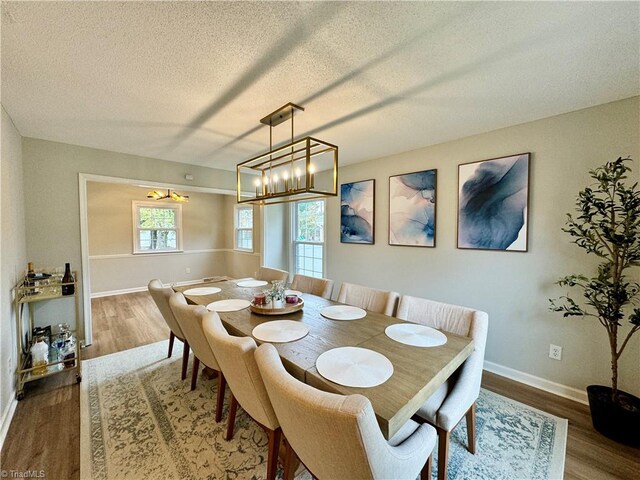 dining room featuring wood-type flooring, a textured ceiling, and a notable chandelier