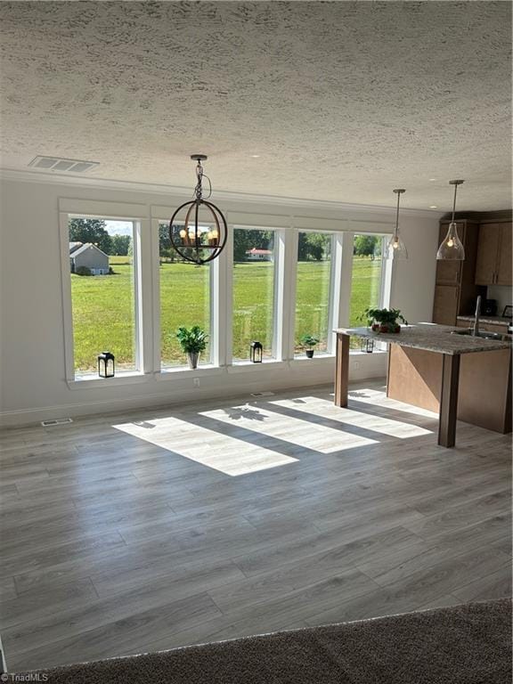 3700 Ireland Rd, Yadkinville, NC 27011 - unfurnished dining area featuring a sink, a textured ceiling, wood finished floors, a chandelier, and baseboards