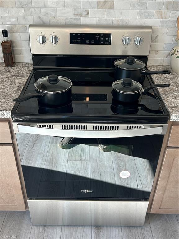3700 Ireland Rd, Yadkinville, NC 27011 - kitchen view of electric range, decorative backsplash, and light stone counters
