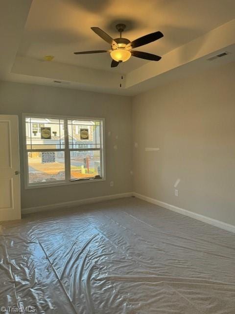 spare room with a tray ceiling and ceiling fan