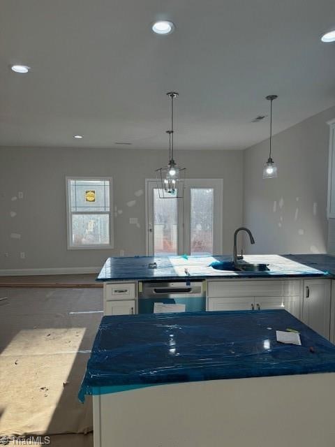 kitchen featuring white cabinets, dishwasher, decorative light fixtures, and a kitchen island with sink