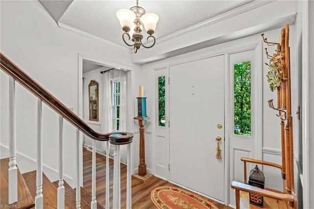 foyer entrance with plenty of natural light, a chandelier, stairs, wood finished floors, and ornamental molding