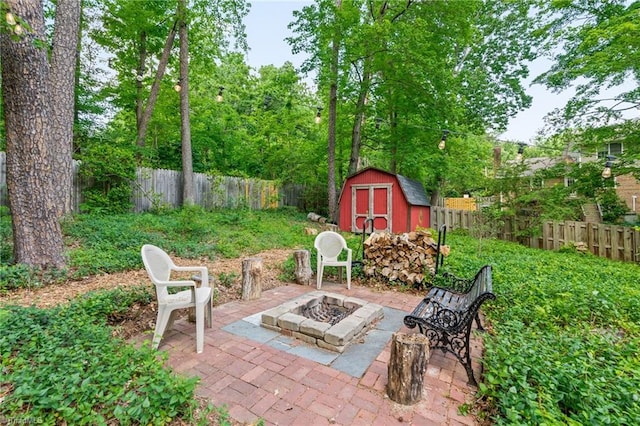 view of patio featuring a storage unit, an outdoor structure, an outdoor fire pit, and a fenced backyard