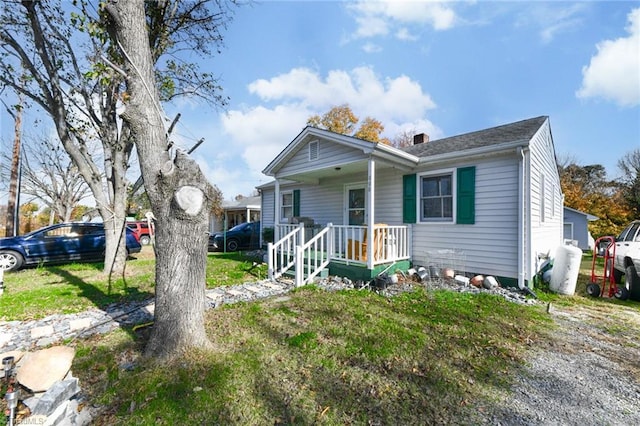 bungalow-style home featuring covered porch and a front lawn