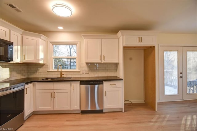 kitchen with stainless steel appliances, sink, white cabinets, and light hardwood / wood-style floors