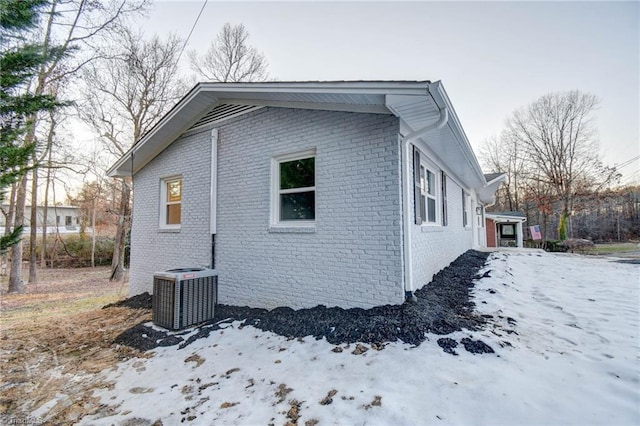 view of snowy exterior with central AC unit