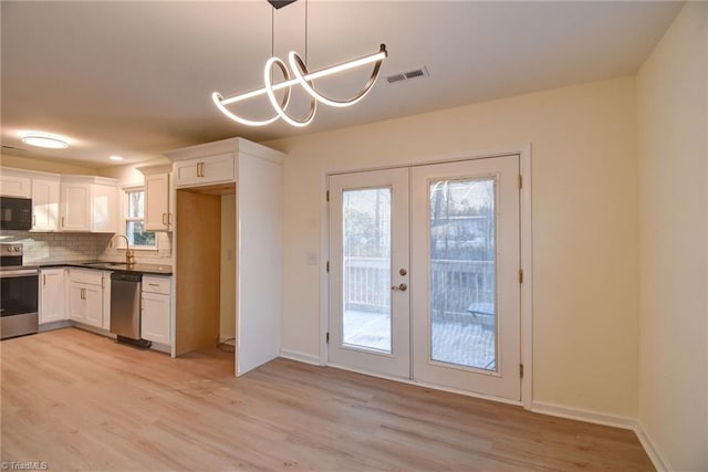 kitchen with french doors, appliances with stainless steel finishes, pendant lighting, light hardwood / wood-style floors, and white cabinets