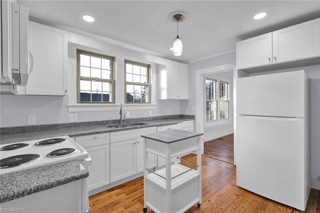 kitchen with white cabinets, light hardwood / wood-style floors, white appliances, and sink