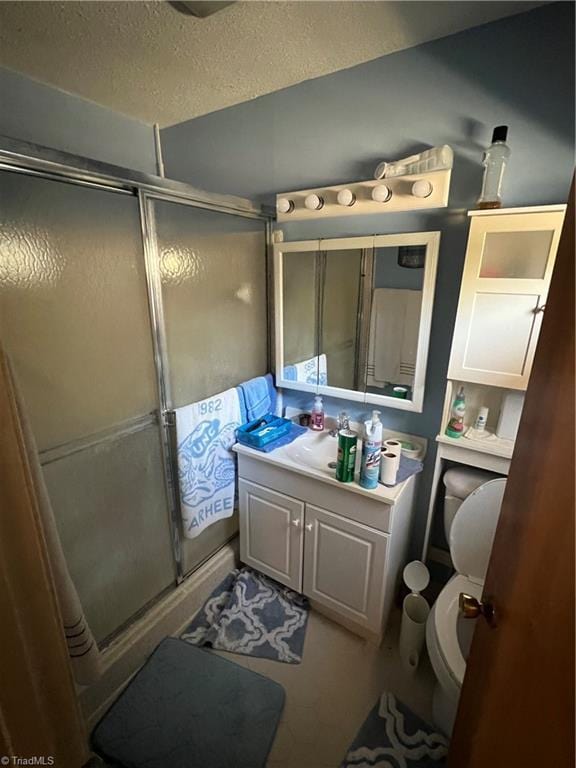 full bathroom featuring toilet, a shower stall, a textured ceiling, and vanity