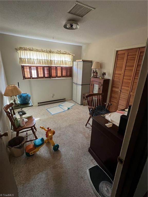 interior space featuring carpet, visible vents, a baseboard heating unit, and a textured ceiling