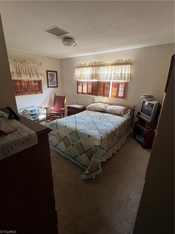 bedroom featuring carpet, visible vents, and a textured ceiling