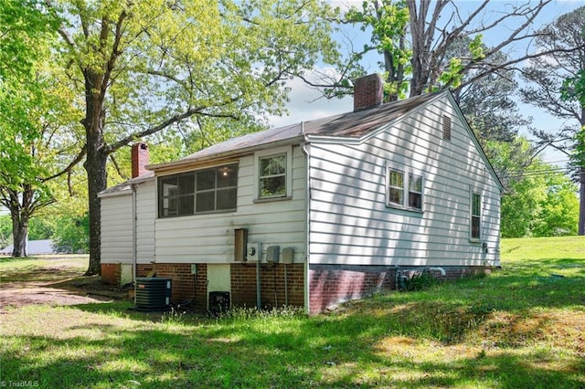 view of property exterior with a lawn and central AC