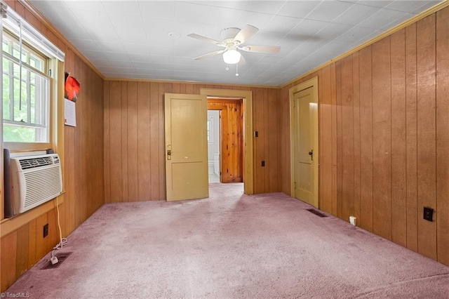 spare room featuring ceiling fan, cooling unit, light colored carpet, and wooden walls