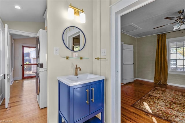 bathroom with vanity, wood finished floors, stacked washer / drying machine, and ceiling fan