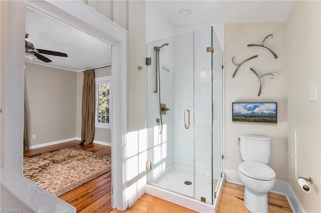 bathroom featuring a stall shower, toilet, baseboards, and wood finished floors