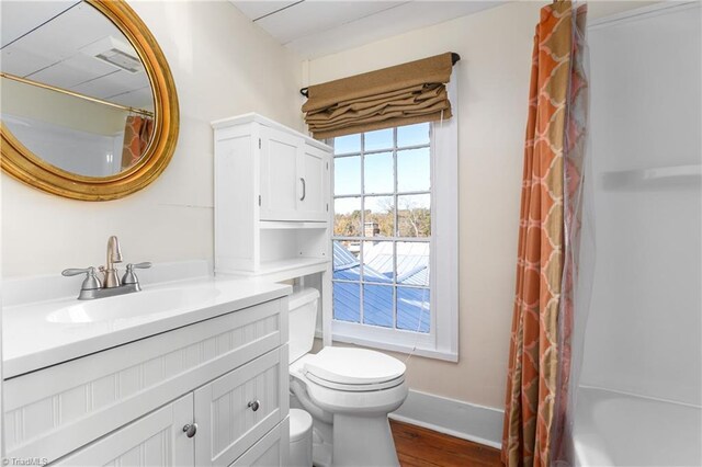 bathroom featuring toilet, wood finished floors, a shower with shower curtain, baseboards, and vanity