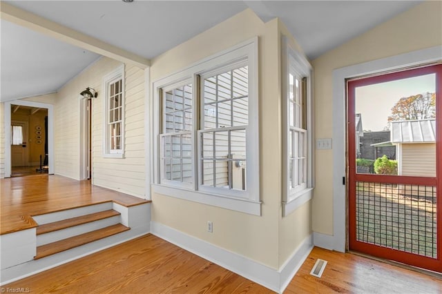 doorway to outside with vaulted ceiling, visible vents, baseboards, and wood finished floors