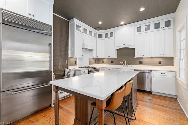 kitchen with white cabinetry, a kitchen island, light wood-type flooring, and stainless steel appliances