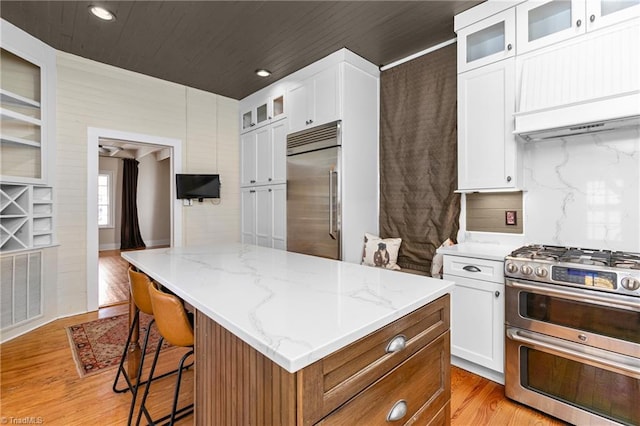 kitchen featuring visible vents, light wood finished floors, a kitchen island, stainless steel appliances, and white cabinetry