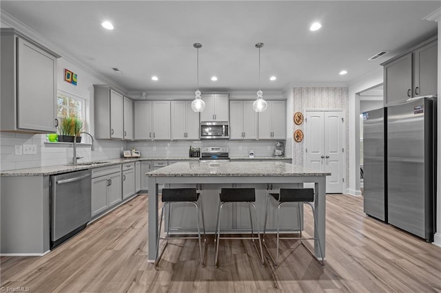 kitchen featuring crown molding, sink, hanging light fixtures, a kitchen island, and stainless steel appliances