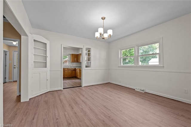 unfurnished dining area featuring light hardwood / wood-style flooring and a notable chandelier