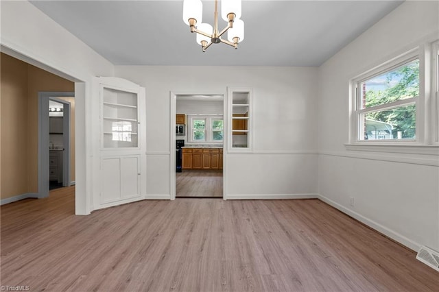 interior space with a wealth of natural light, an inviting chandelier, and light hardwood / wood-style floors