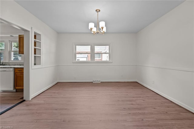 unfurnished dining area featuring light wood-type flooring, a wealth of natural light, and an inviting chandelier